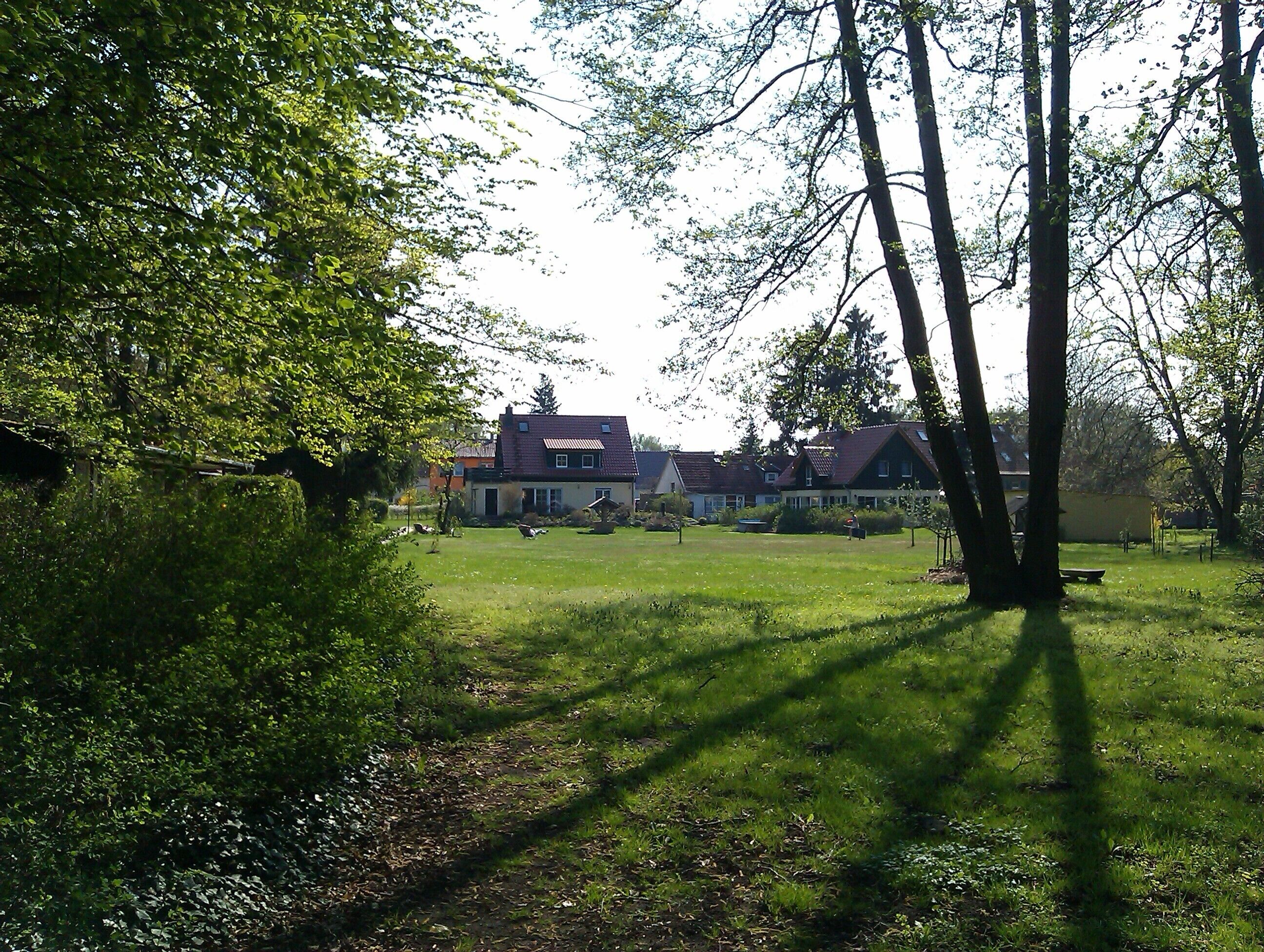 A house with a red roof, surrounded by a grassy yard and trees.