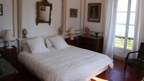 A neatly arranged bedroom with a large bed, a nightstand with a lamp, a dresser, and a chair. - House / Villa - Menton (Menton)
