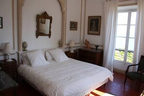 A neatly arranged bedroom with a large bed, a nightstand with a lamp, a dresser, and a chair. - House / Villa - Menton (Menton)