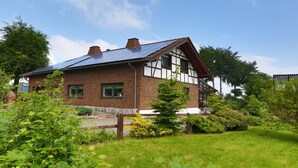 Una casa tradicional con entramado de madera, techo inclinado y paneles solares.