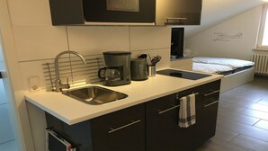 Una cocina moderna con un lavamanos integrado, una cafetera y un hervidor. Hay una ventana con vistas al exterior.