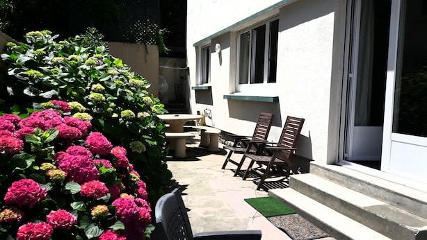 An outdoor patio with a table and chairs, a small garden with hydrangea plants, and a white building with windows and a door. - T3 with terrace, sea view, hyper center biarritz, old port, 20m from the beach. (Biarritz)