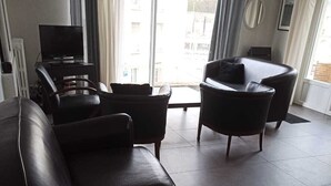 Un salon moderne avec un canapé en cuir, une petite table et un téléviseur.