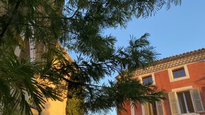 Eine schmale Straße, gesäumt von Gebäuden unterschiedlicher Architektur, darunter ein Haus mit Ziegeldach und ein weiteres mit Stuckfassade.
