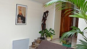 Una sala de estar con un sofá marrón, una escultura de madera y una planta en maceta.