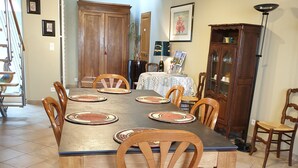 Un comedor con una gran mesa de madera, seis sillas y un aparador con puertas de cristal.
