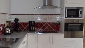 Una cocina con gabinetes blancos, una campana extractora de acero inoxidable, un microondas y un horno.