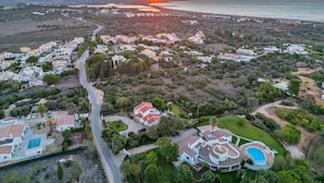 Vista aérea de una zona residencial costera con casas, una carretera y una gran piscina.
