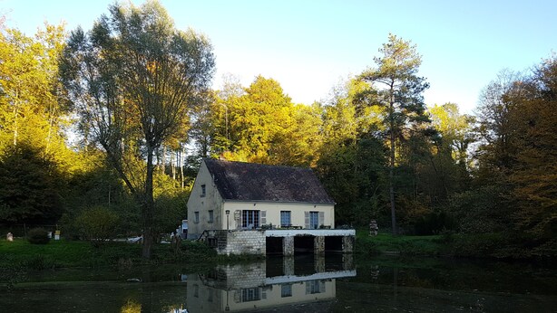 A house with a stone foundation, a sloped roof, and a small dock extending into a calm river. - House nest in the forest, near castel Compiègne, Pierrefonds and Chantilly (Saint-Jean-aux-Bois)