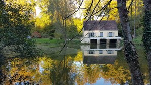 A house reflected in a calm body of water, surrounded by trees and greenery. - House nest in the forest, near castel Compiègne, Pierrefonds and Chantilly (Saint-Jean-aux-Bois)