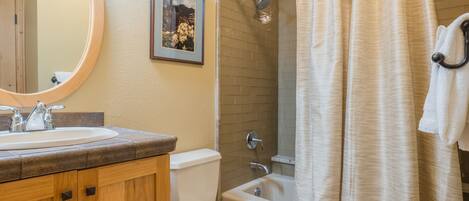A bathroom with a sink, toilet, bathtub, and shower curtain.