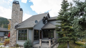 A modern house with a stone chimney, a covered porch, and a well-maintained lawn. - Private Home With A Beautiful Mountain Vista - Woods24 by RedAwning (Copper Mountain)