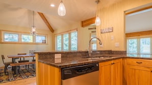 A kitchen with wooden cabinets, a granite countertop, a dishwasher, and a window with a view of trees. - Private Home With A Beautiful Mountain Vista - Woods24 by RedAwning (Copper Mountain)