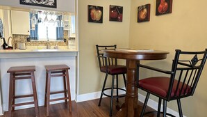 A dining area with a round wooden table, four chairs, and two bar stools. - Comfortable Daphne Condo near Bay, Fairhope, and Mobile;  Short Drive to Beaches (Daphne)