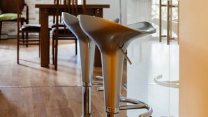 Eine moderne Küche mit zwei metallenen Barhocker, einem Holzessttisch und Stühlen.