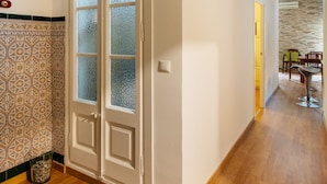 Ein Flur mit Holzboden, einer weißen Tür mit satinierten Glasscheiben und einer gefliesten Wandverkleidung.