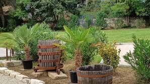 Un jardí amb palmeres, un cupó de fusta i una paret de pedra.