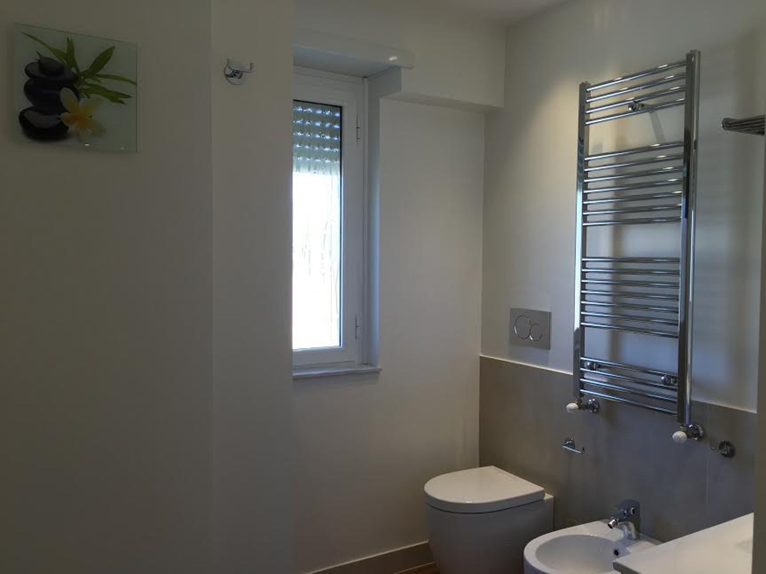 A modern bathroom with a toilet, sink, and a chrome towel rack.