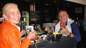 Un bar con mostrador, vasos y botellas.