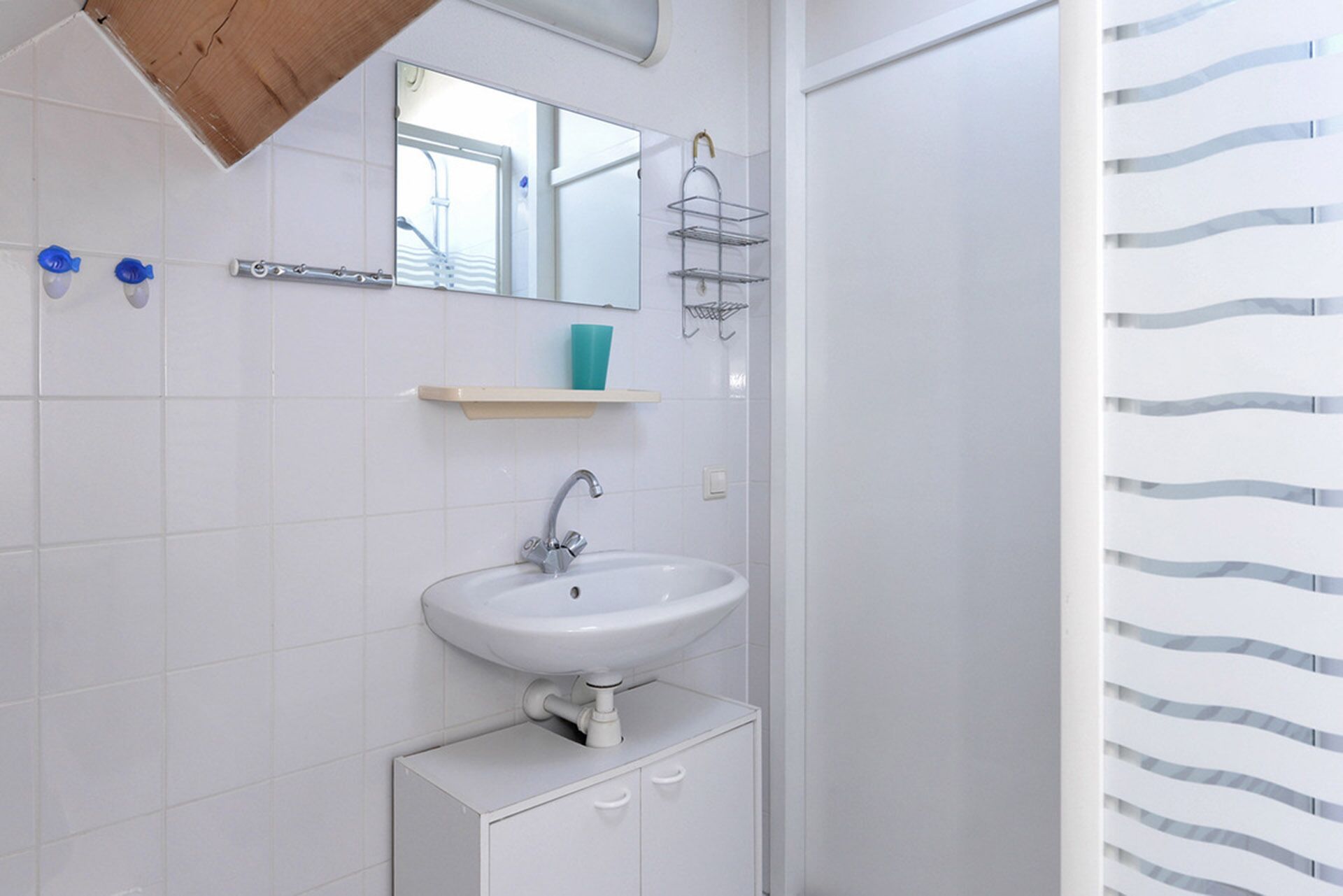Ein Badezimmer mit einem weißen Waschbecken, Spiegel und Handtuchhalter.