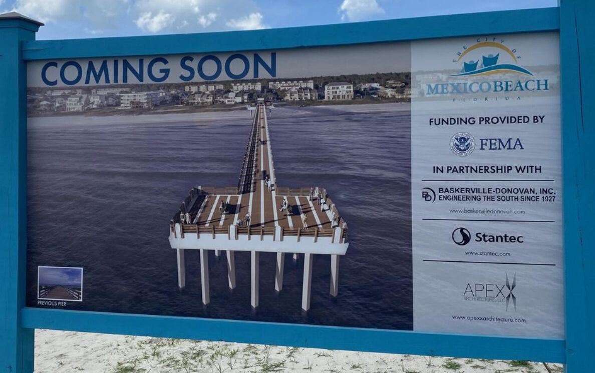 A pier with a sign indicating a new development in Mexico Beach, Florida, funded by FEMA and partners.