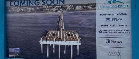 A pier with a sign indicating a new development in Mexico Beach, Florida, funded by FEMA and partners.