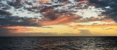 A sunset over the ocean with a cloudy sky.