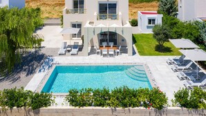 A modern two-story building with a swimming pool, outdoor seating, and a well-maintained lawn. - Lovingly furnished house in a quiet location with heated pool and sea views (Gennadi, Rhodos)