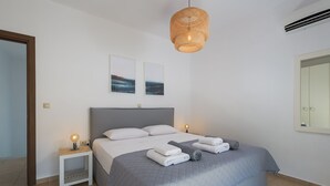 A modern bedroom with a large bed, two bedside tables, a hanging light fixture, and artwork on the wall. - Lovingly furnished house in a quiet location with heated pool and sea views (Gennadi, Rhodos)
