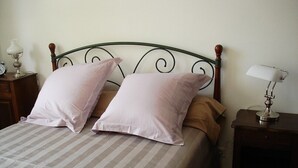 A bed with a striped bedspread, two pillows, a wooden headboard, and a nightstand with a lamp. - Apt T3 air-conditioned, on the 1st floor of a character residence in CAHORS  (Cahors)