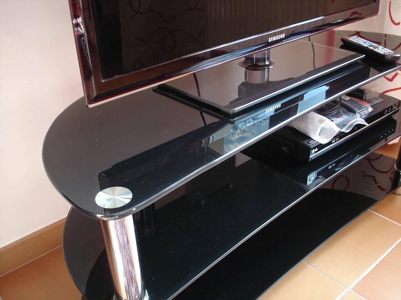 A black entertainment center with a flat-screen TV, a DVD player, and a remote control.