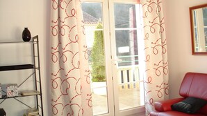 A living room with a red sofa, a bookshelf, and a sliding glass door leading to an outdoor area. - Apt T3 air-conditioned, on the 1st floor of a character residence in CAHORS  (Cahors)