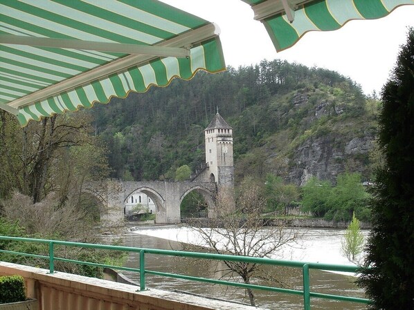 A stone bridge with a tower, a river, and a green railing.