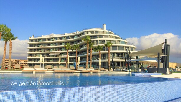 A modern hotel with a pool, palm trees, and a clear blue sky. - Exclusive apartment with frontal sea views (3 bedrooms / 2 bathrooms) (Arenales del Sol)