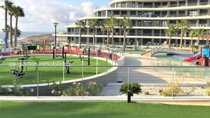 A modern building with multiple balconies, a swimming pool, and a playground area with exercise equipment. - Exclusive apartment with frontal sea views (3 bedrooms / 2 bathrooms) (Arenales del Sol)