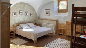 Quarto acolhedor com cama de madeira, mesa de cabeceira, cômoda e janela com vista para o verde.