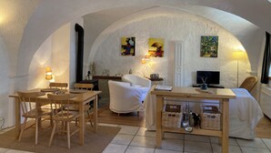 Um quarto acolhedor, com arco, com área de jantar, um sofá e uma TV.