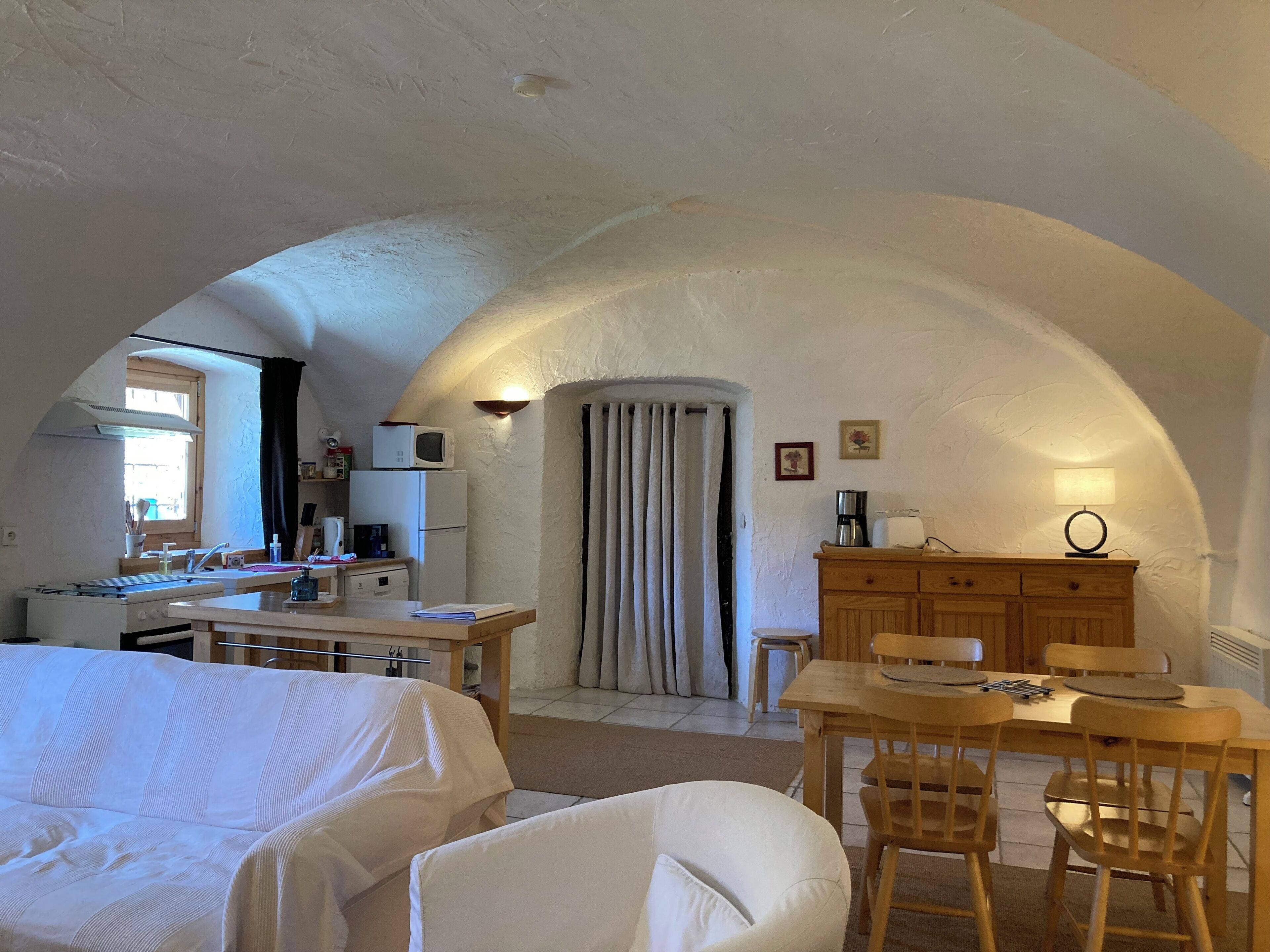 A cozy, well-lit room with a kitchen area, a dining table, and a sofa.