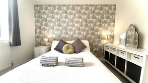 A neatly arranged bedroom with a bed, pillows, bedside tables, and a dresser. - Mill Lane Cottage, a pretty cottage in beautiful countryside, 4 miles from Bath. (Bath)