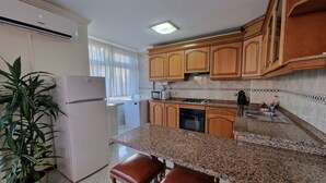 A kitchen with wooden cabinets, a granite countertop, a refrigerator, a microwave, a dishwasher, and a sink. - "Beachfront apartment - Praia do Furadouro with Wi-Fi" (Ovar)