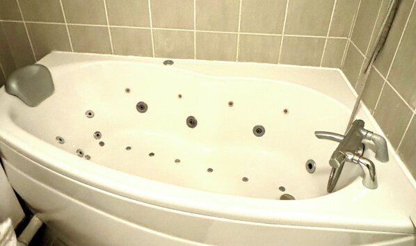 A white bathtub with multiple drain holes, a faucet, and a soap dish.