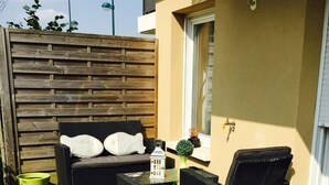 Un patio con mobiliario exterior, una mesa pequeña y una planta en maceta.
