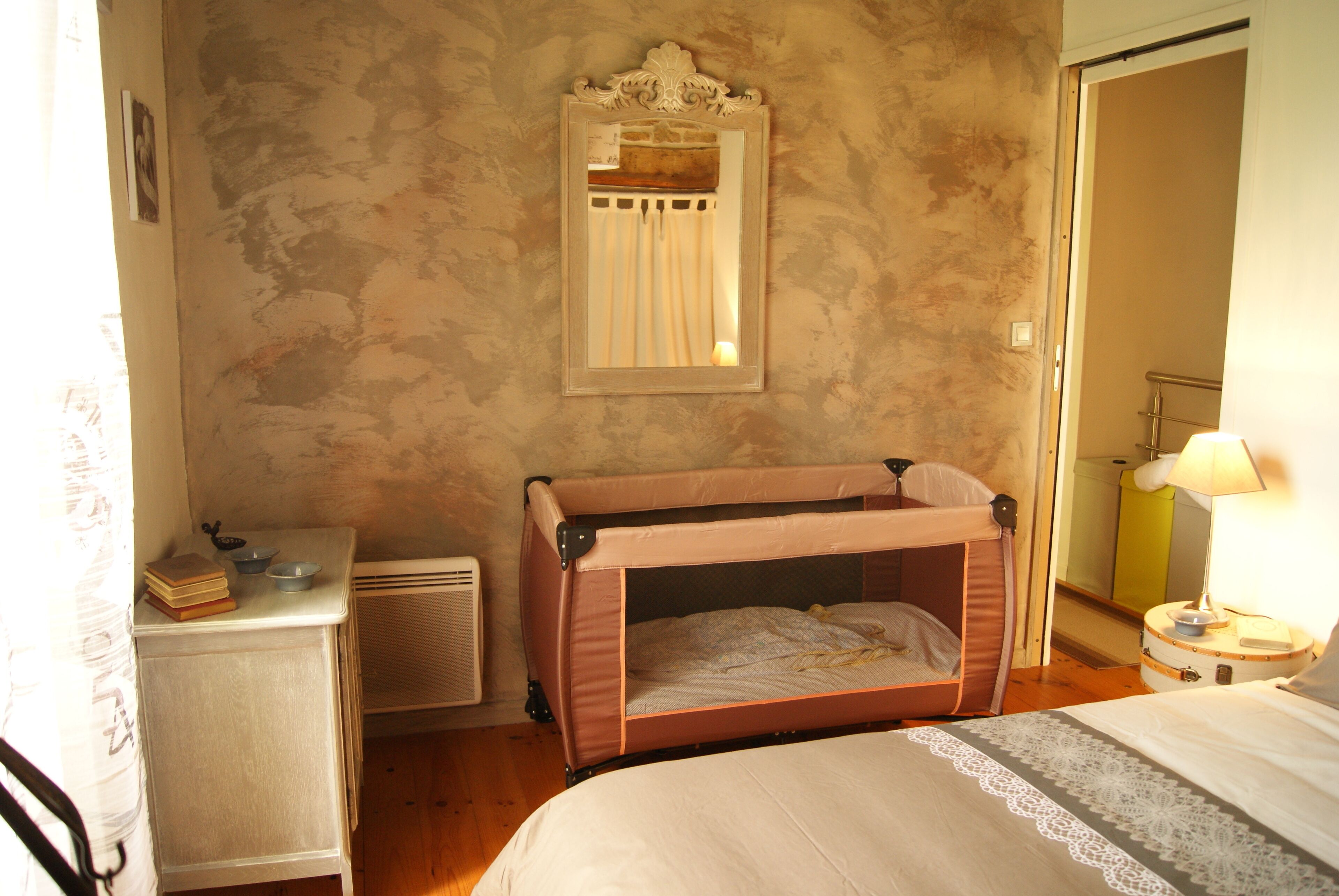 A bedroom with a bunk bed, a bedside table with a lamp, a mirror, and a small cabinet.