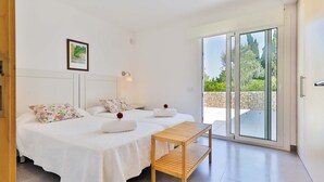 Ein Schlafzimmer mit zwei Betten, einem kleinen Tisch und einer Glasschiebetür, die auf einen Balkon führt.