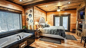 Une chambre à coucher dans un chalet en bois, avec un lit, une coiffeuse avec un miroir, une baignoire et une cheminée.