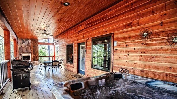 Une cabane en bois dotée d’un bain à remous, d’un barbecue et d’un espace patio.