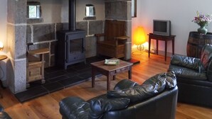 A cozy living room with a stone fireplace, leather sofa, and a television.