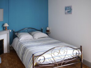 Un lit simple avec un cadre en métal, une couvre-lit à rayures et deux lampes de chevet.