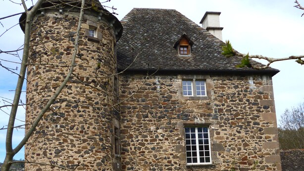 A stone building with a tower, a wooden door, and a window with bars.