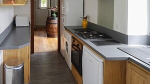 A modern kitchen with a dishwasher, stove, and a wooden barrel.